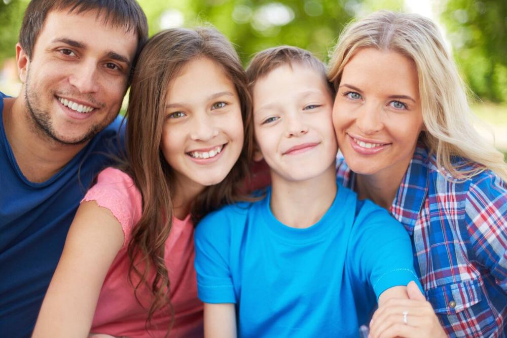 family of four smiling outside in an anderson park