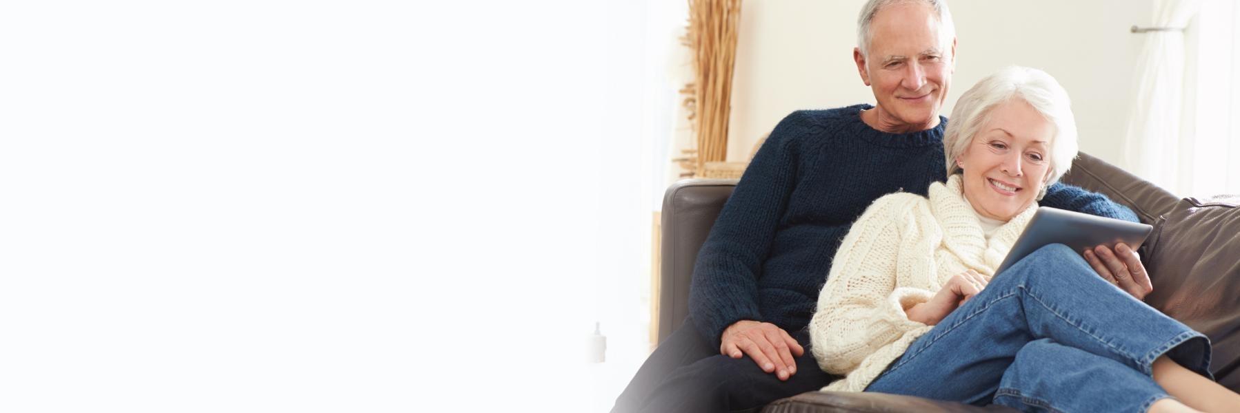 older man and woman looking at tablet while sitting on couch in their anderson home
